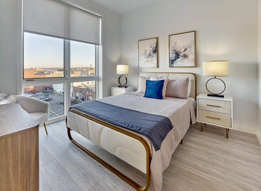 Cozy bedroom with plush bedding and large windows at Ora luxury apartments in Hackensack, NJ