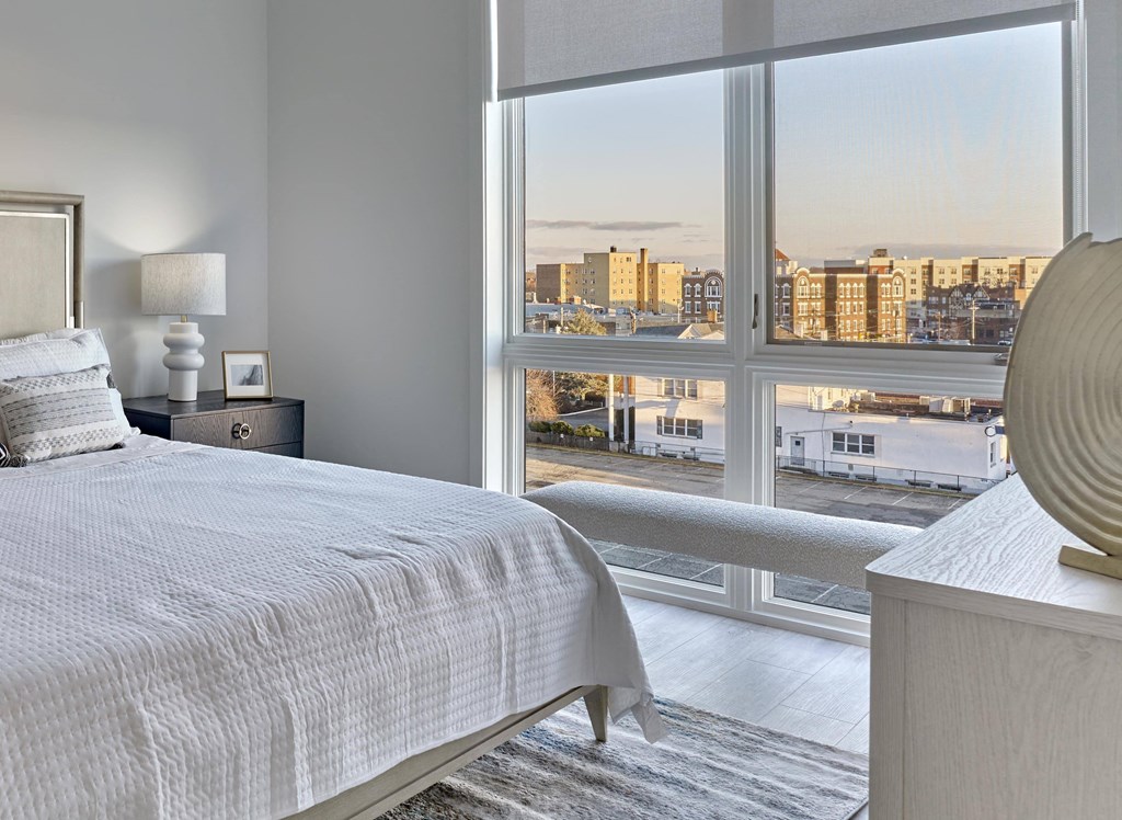 Residences Bright bedroom with cozy bedding and natural light at Ora luxury apartments in Hackensack, NJ