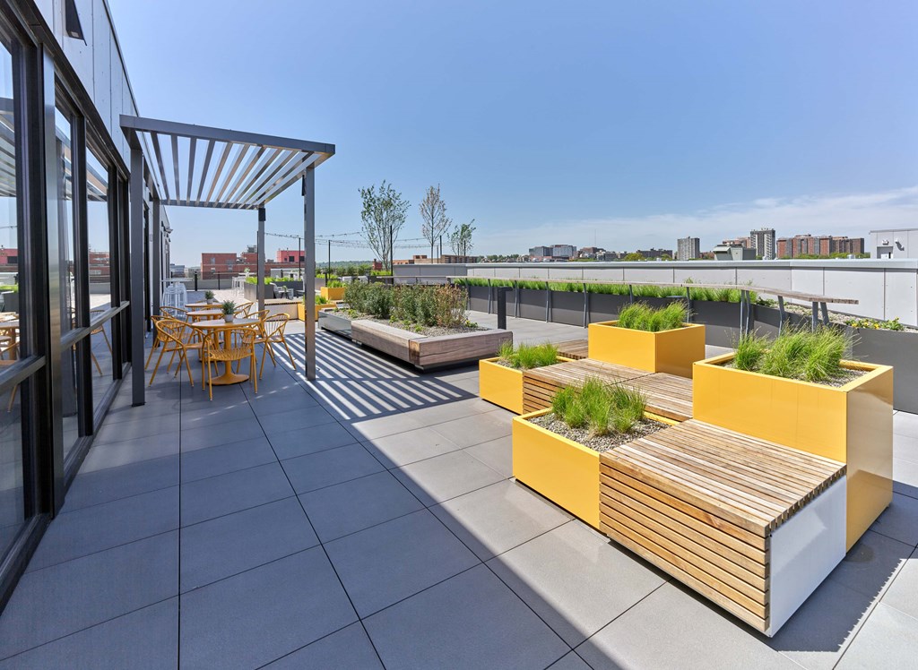 A patio with a table and chairs and a bench with a planter on it.
