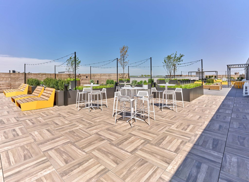 A patio with a herringbone patterned floor and white chairs.