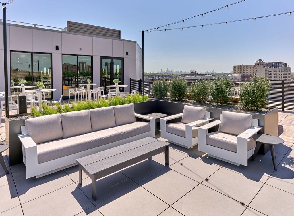 A white outdoor furniture set is on a rooftop patio.