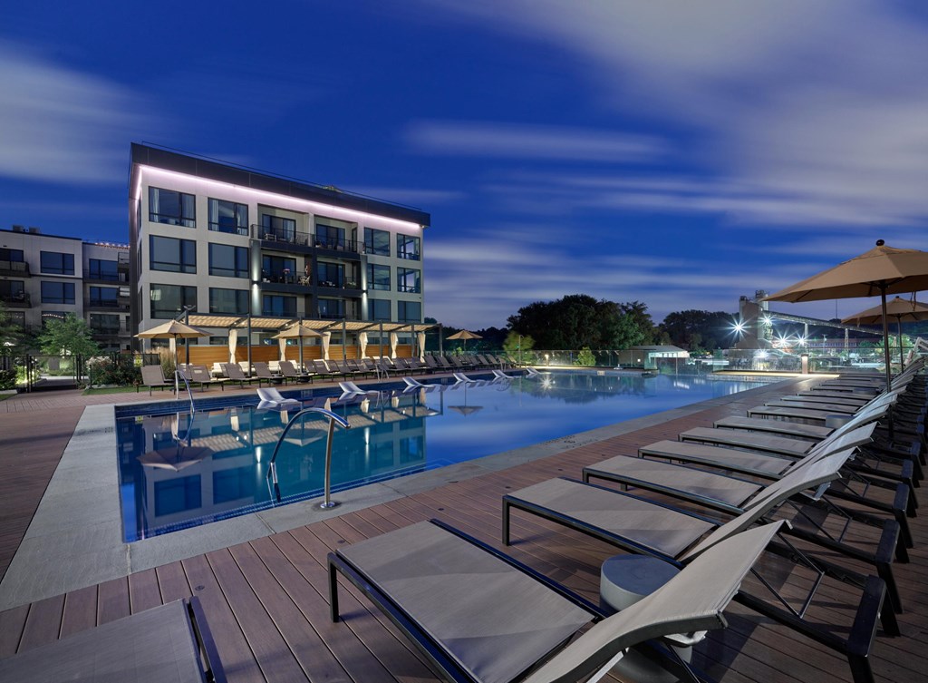 A poolside area with lounge chairs and a building in the background.