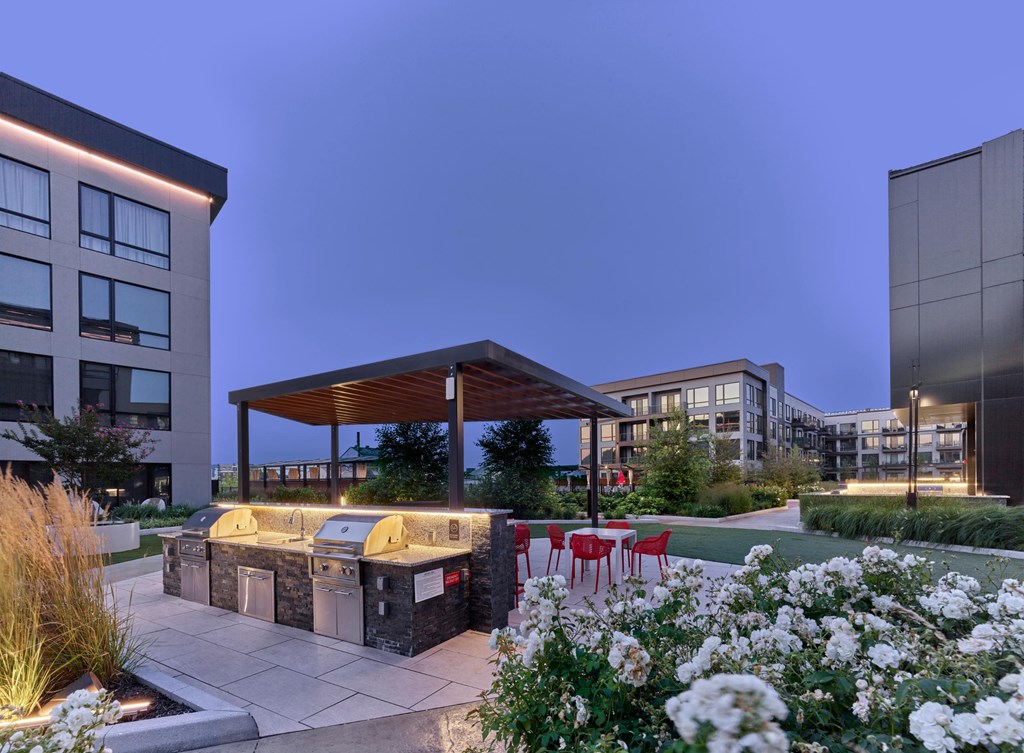 A modern outdoor seating area with a barbecue grill and red chairs.