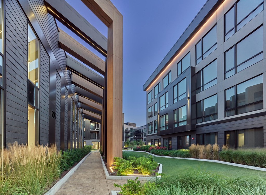A modern building with a long walkway and grassy area in front.