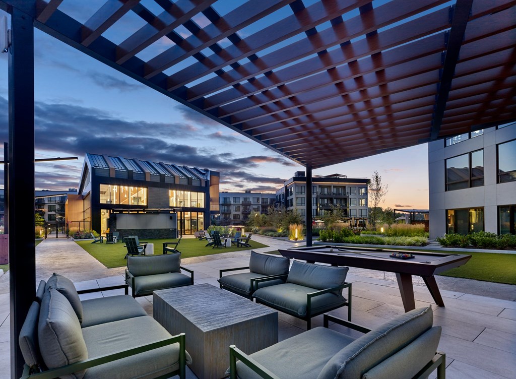 A modern outdoor seating area with a pool table and comfortable chairs.