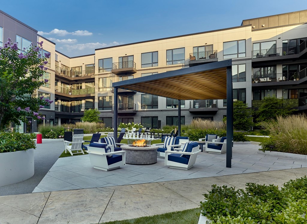 A patio with a fire pit and seating area in front of apartment buildings.