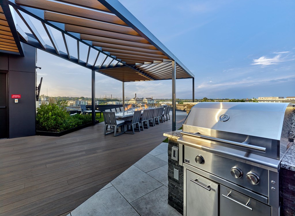 A modern outdoor kitchen with a grill and seating area.