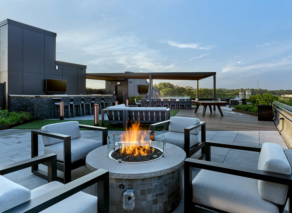 A fire pit sits in the middle of a patio surrounded by chairs.