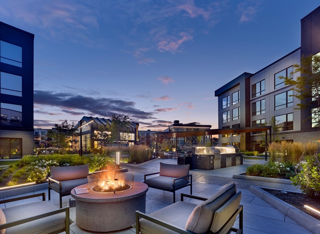 A modern outdoor seating area with a fire pit in the center.