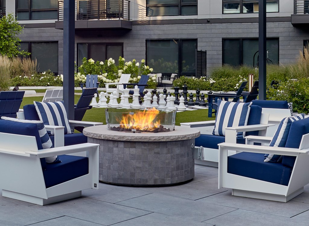 A fire pit sits in the middle of a patio surrounded by chairs.