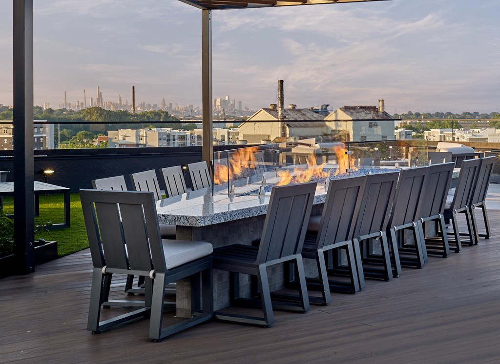 A table with chairs and a fire pit on a wooden deck.