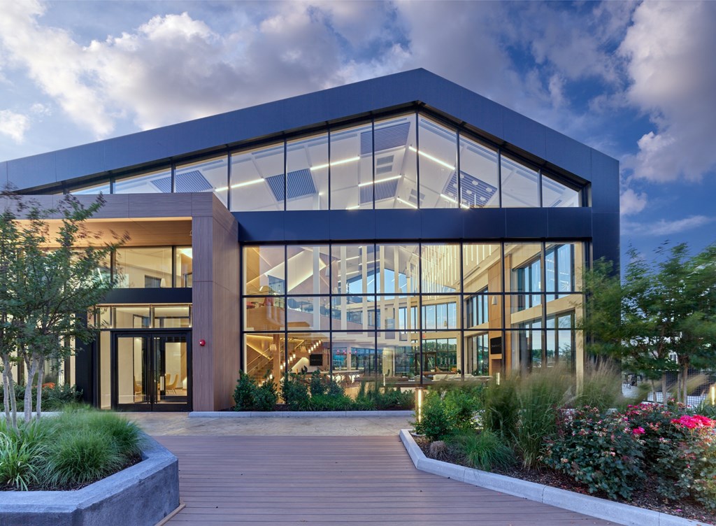 A modern building with a glass facade and a wooden walkway leading to the entrance.