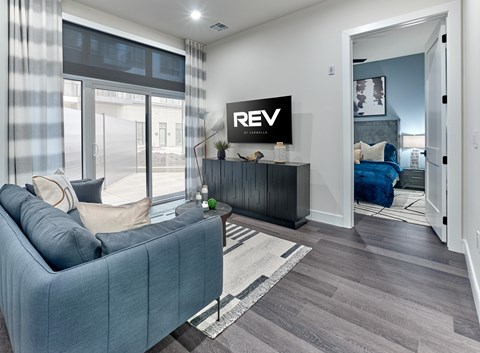 A living room with a blue couch and a TV on the wall.