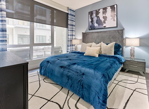 A bedroom with a large bed and a painting on the wall.