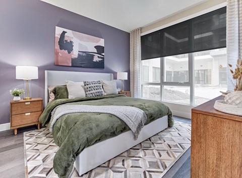 A bedroom with a large bed and a painting on the wall.