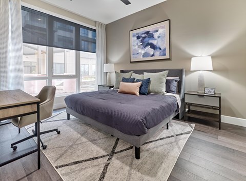 A bedroom with a bed, chair, and painting on the wall.