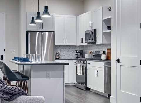 A modern kitchen with a stainless steel refrigerator and white cabinets.