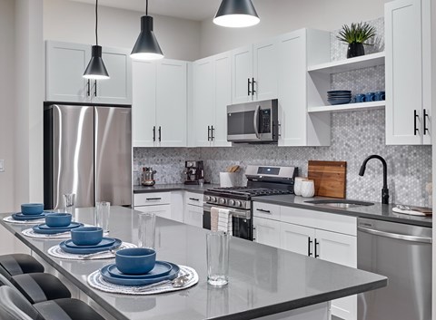 A modern kitchen with a stainless steel refrigerator and white cabinets.