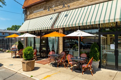 Cafe with striped awning and tables and chairs outside.
