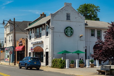 A blue car is parked in front of a Starbucks Coffee shop.