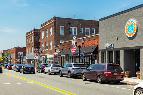 Cars parked on a street in front of a bakery.