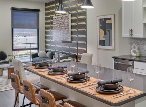 A modern dining room with a long table set for a meal.