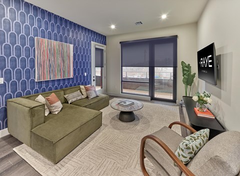A living room with a green couch and a painting on the wall.
