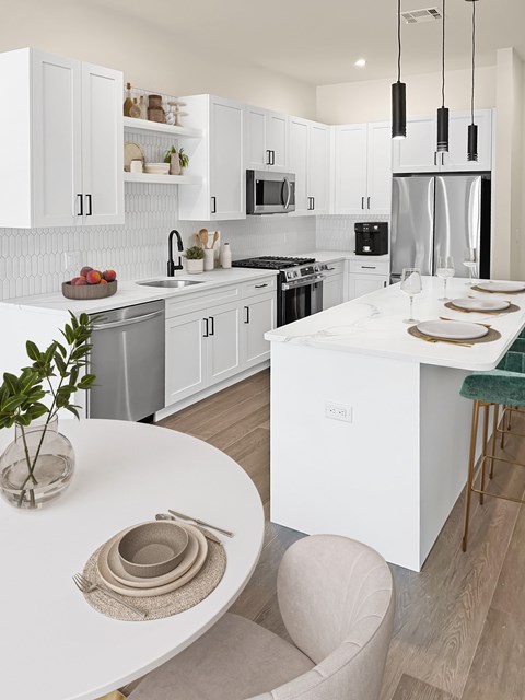 A modern kitchen with a white island and a dining table set for two.