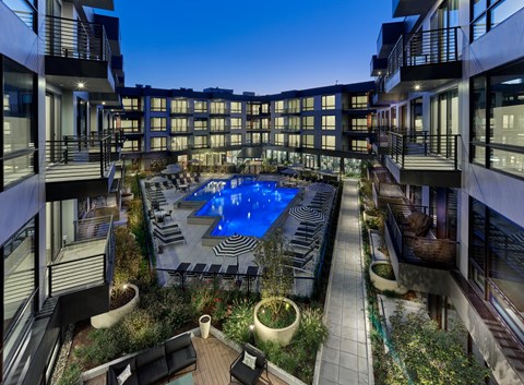 A swimming pool surrounded by balconies and potted plants.