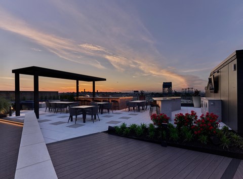 a rooftop terrace with tables and chairs and a sunset