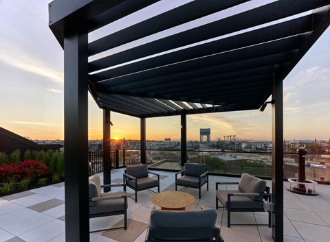 a rooftop terrace with chairs and a table and a sunset