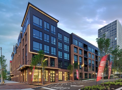 a rendering of a building on a city street at dusk
