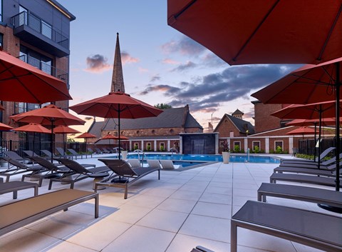 a swimming pool with umbrellas at a hotel with a church in the background