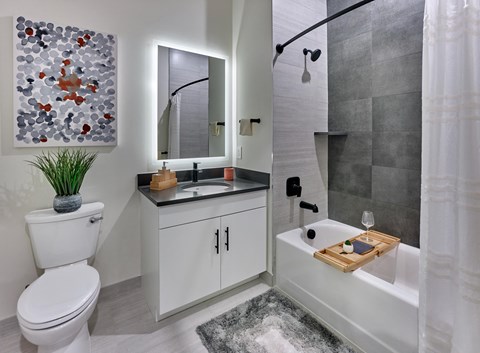 Spacious bathroom with backlit vanity, tiled shower and tub, in luxury apartment at Vermella Broad Street, Newark NJ