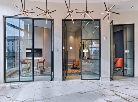 a lobby with glass doors and chairs and a fireplace