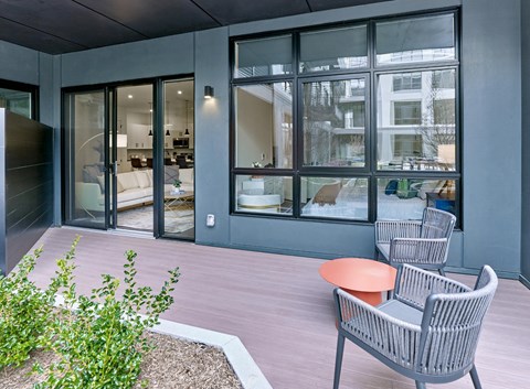 a patio with two chairs and a table in front of glass doors