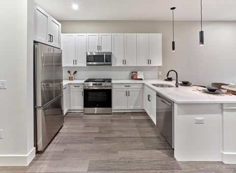 A modern kitchen with white cabinets and stainless steel appliances.