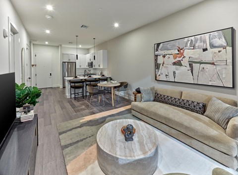 A modern living room with a grey couch and a large abstract painting on the wall.
