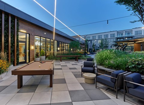 A pool table is surrounded by chairs in a patio area.