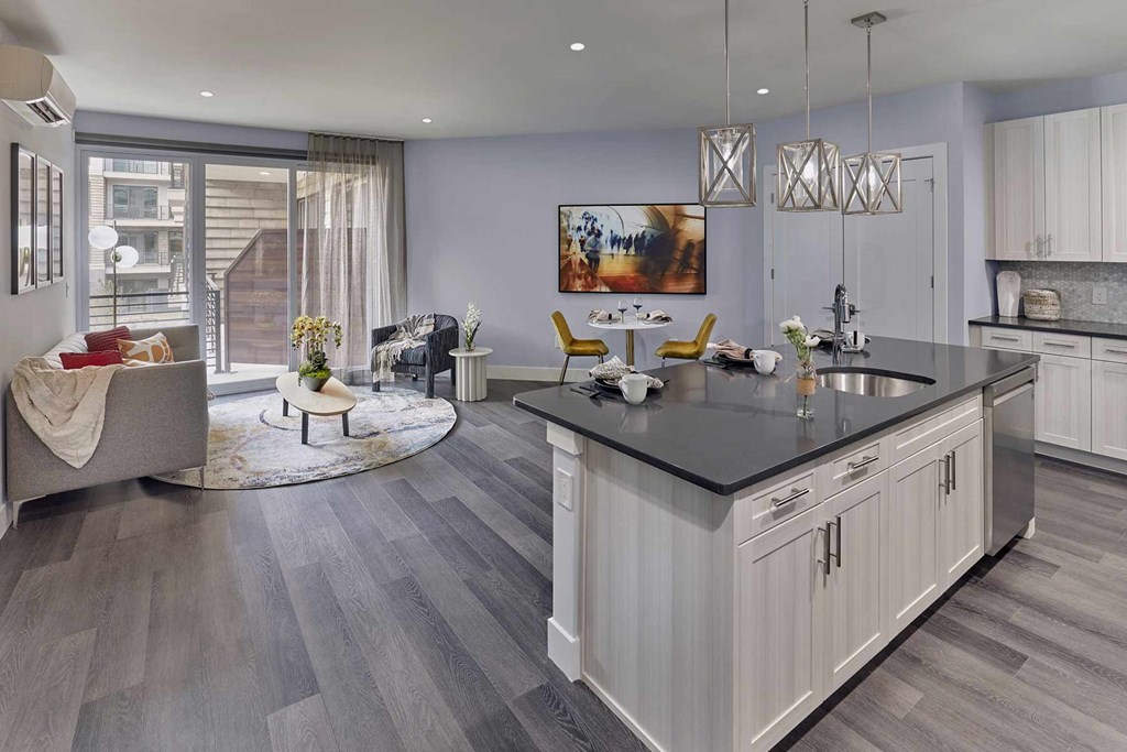 A modern kitchen with a large island and a living area with a couch and chairs.