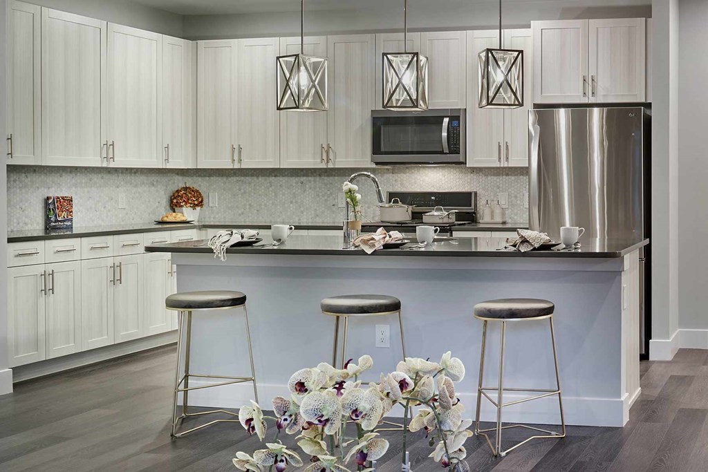 A kitchen with white cabinets and a black countertop.