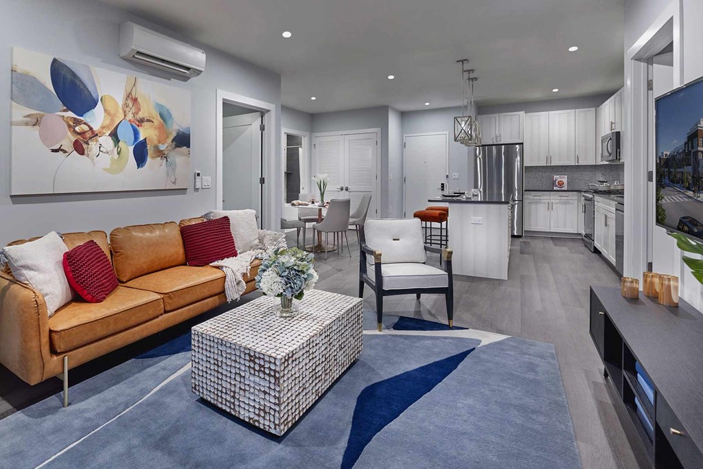 A modern living room with a tan couch and a blue rug.