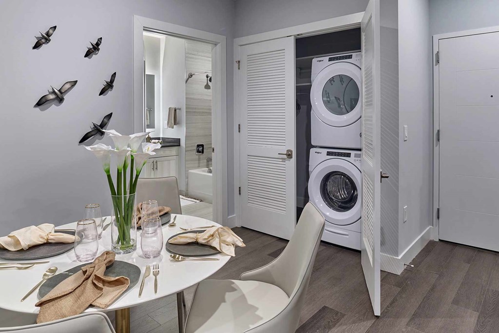 A modern dining room with a white table set for two and a wall decorated with black bird decals.