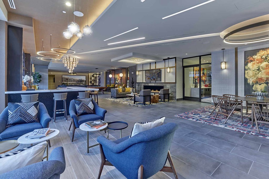 A modern living room with blue chairs and a fireplace.