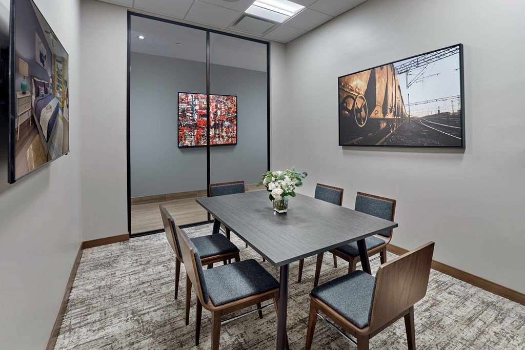A conference room with a table, chairs, and two pictures on the wall.