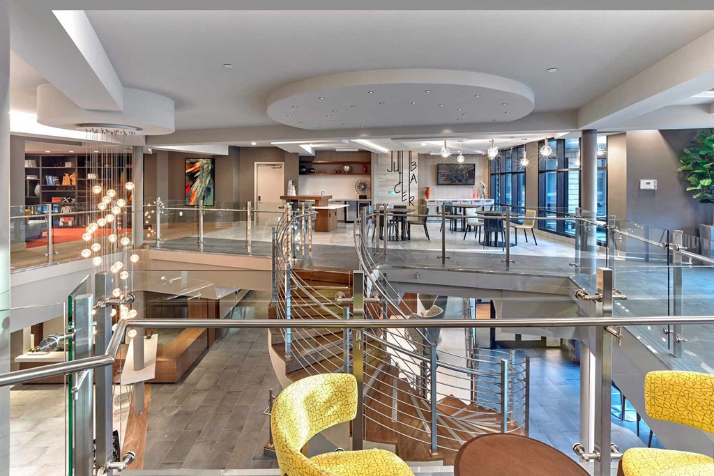 A modern interior with a spiral staircase and yellow chairs.