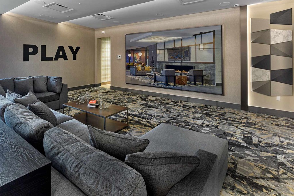 A living room with a grey sofa and a coffee table in front of a large painting.