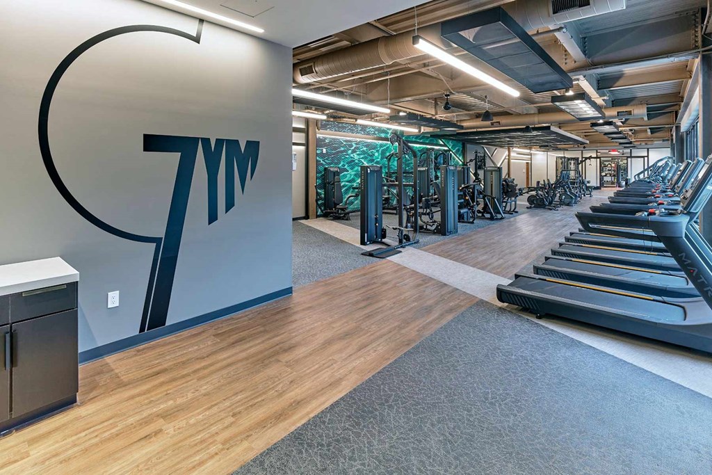 A gym with treadmills and a wall with 7ym on it.