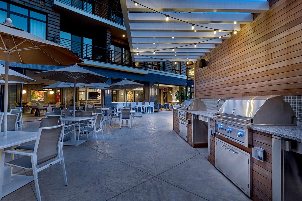 A patio with tables and chairs and umbrellas.