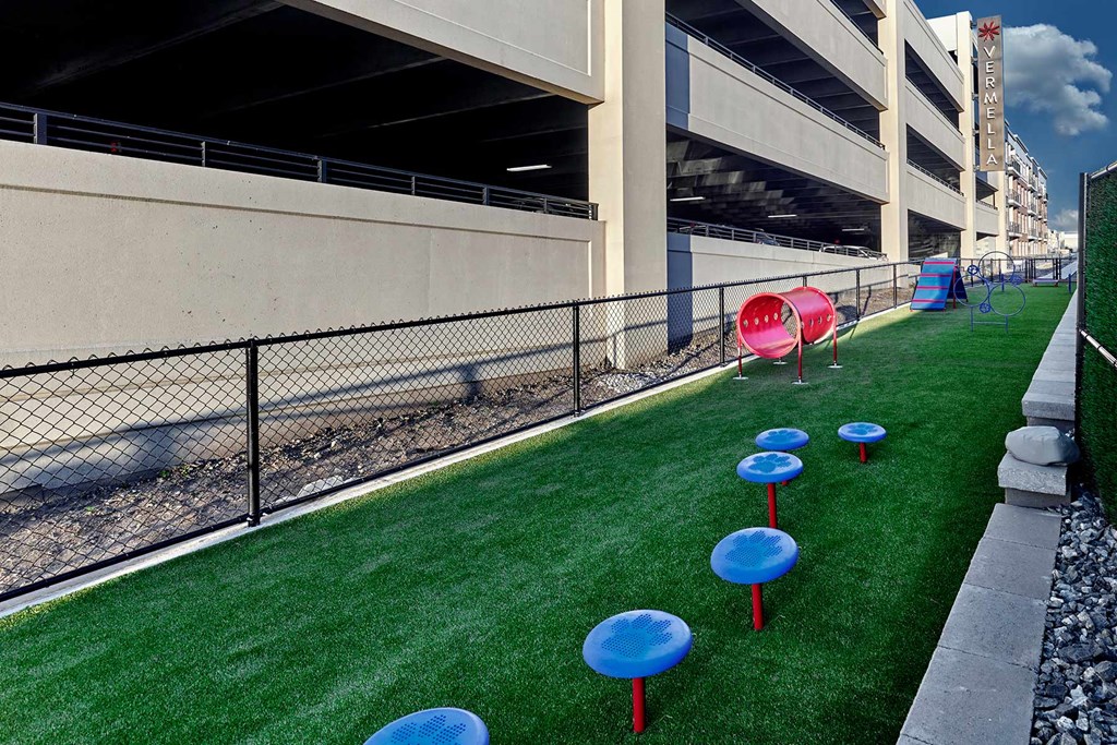 A row of blue and red tables are lined up on a green lawn.